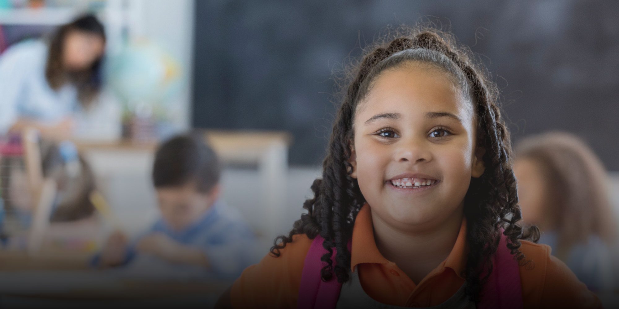 Smiling student with a backpack in a classroom.